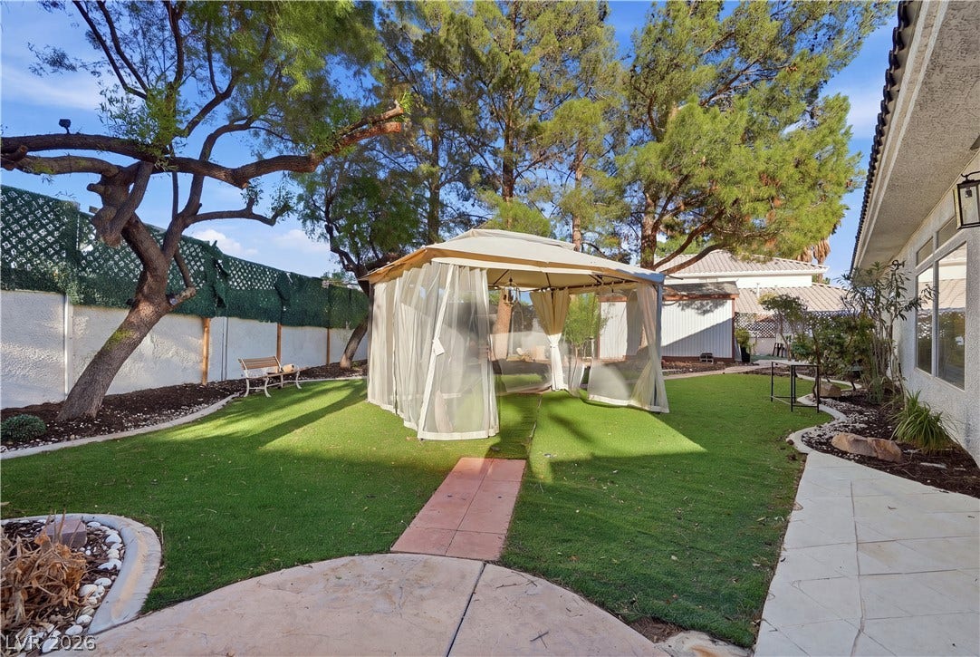 Mature trees shade a tidy lawn space complete with a gazebo and paved walkways.