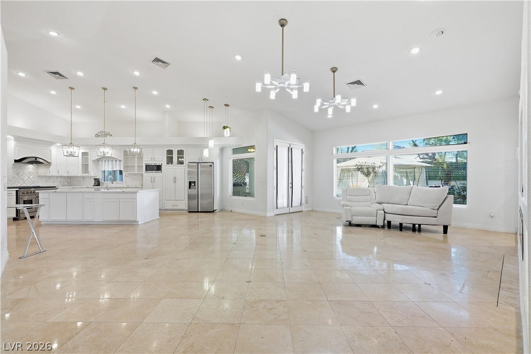 Polished tile flooring and dual chandeliers elevate this generous open-concept living space.