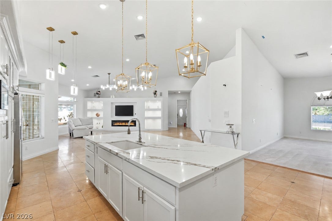 Gleaming stone counters anchor an airy open floorplan under soaring high ceilings.