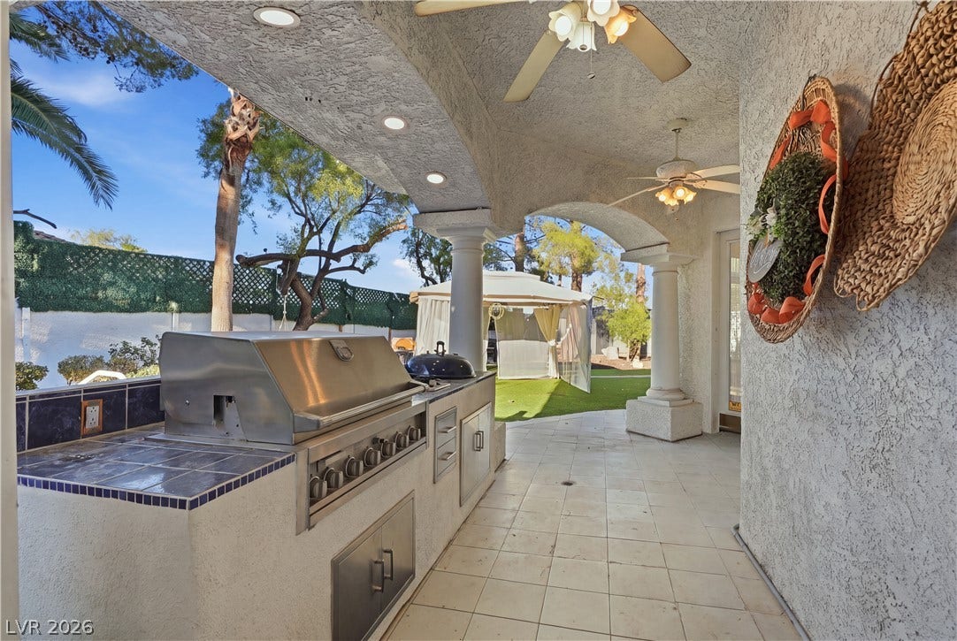 An arched covered patio provides a shaded outdoor kitchen overlooking the yard.