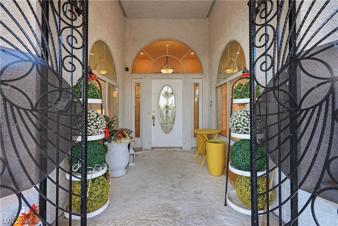 An inviting gated portico guides guests directly toward a grand arched glass entryway.