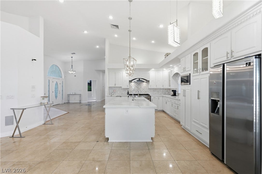 Stone tile flooring and high ceilings define this open, light-filled kitchen space.