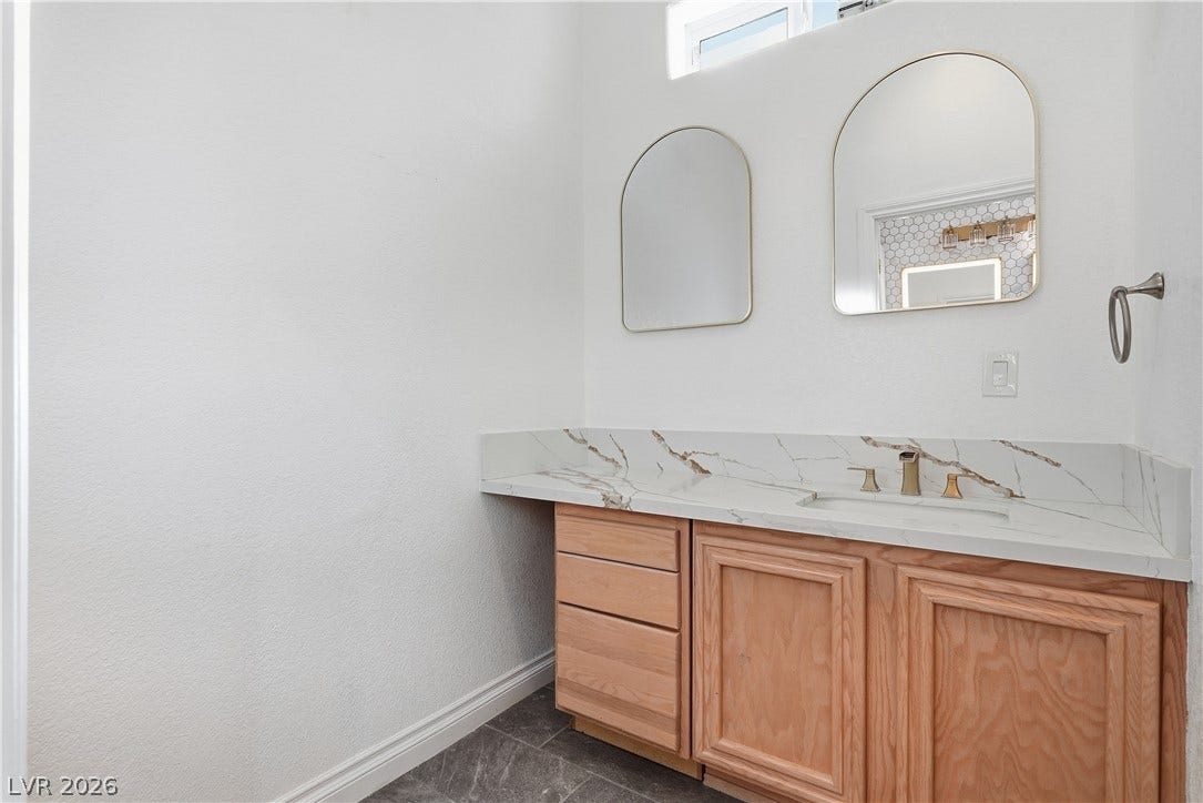 Elegant stone counters and warm wood cabinetry elevate this modern bathroom design.