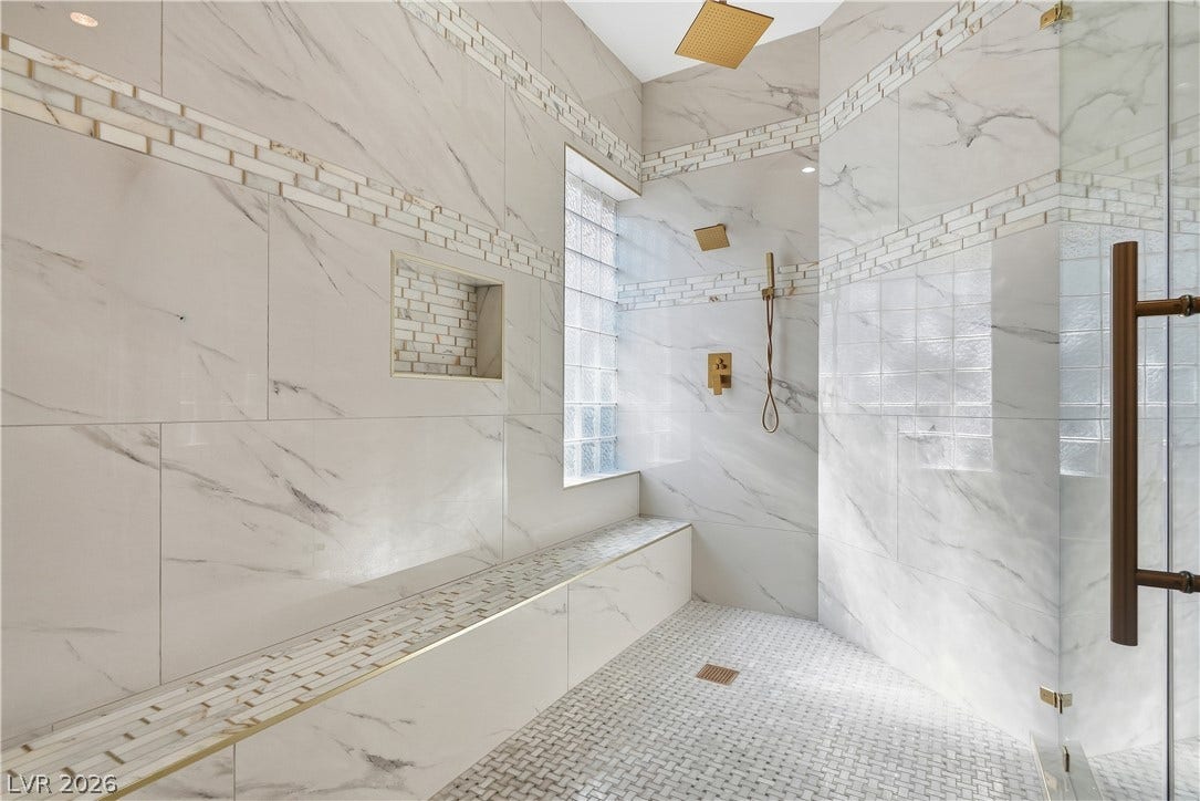 Ornate marble tiling and premium brass fixtures create a luxurious walk-in shower experience.