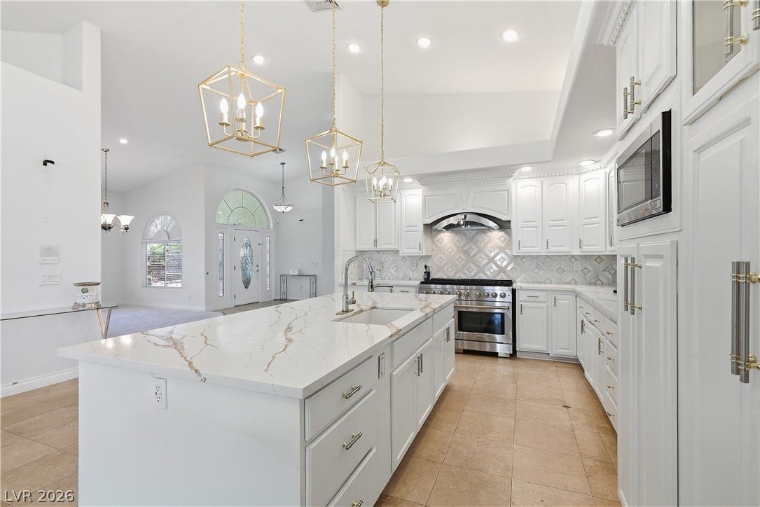 Gleaming stone countertops and classic cabinetry elevate this bright kitchen with vaulted ceilings.