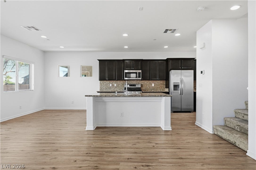 1122 Bradley Bay Avenue, Henderson, NV 89014 An open kitchen featuring a central island sits adjacent to a carpeted staircase.