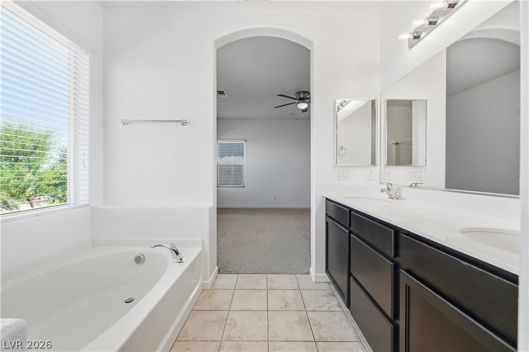 1122 Bradley Bay Avenue, Henderson, NV 89014 An arched doorway leads from the tiled bathroom into an adjacent carpeted room.