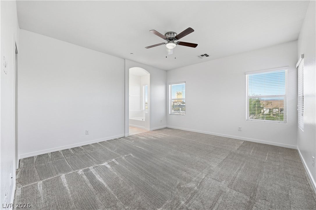 1122 Bradley Bay Avenue, Henderson, NV 89014 Plush carpeted flooring anchors this spacious primary suite with an adjacent bathroom entrance.