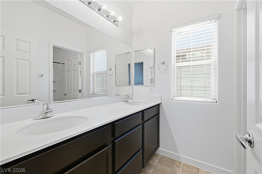 1122 Bradley Bay Avenue, Henderson, NV 89014 A long double vanity with dark cabinetry and light counters coordinates with tiled flooring.