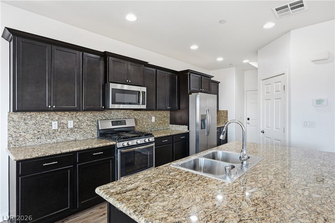 1122 Bradley Bay Avenue, Henderson, NV 89014 Rich dark cabinetry pairs beautifully with expansive granite countertops in this modern culinary space.