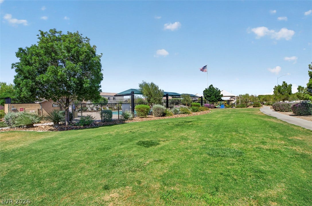 1122 Bradley Bay Avenue, Henderson, NV 89014 An expansive green lawn borders a fenced community pool and a paved walking path.
