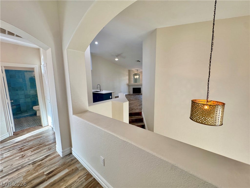 Graceful architectural arches frame a multi-level interior displaying rich wood flooring.
