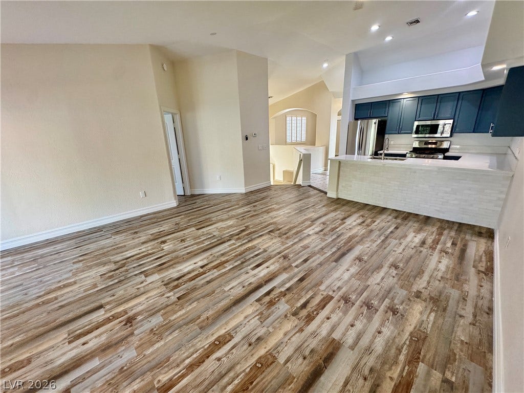 Gleaming wood floors anchor an airy, open layout with a modern breakfast bar kitchen.