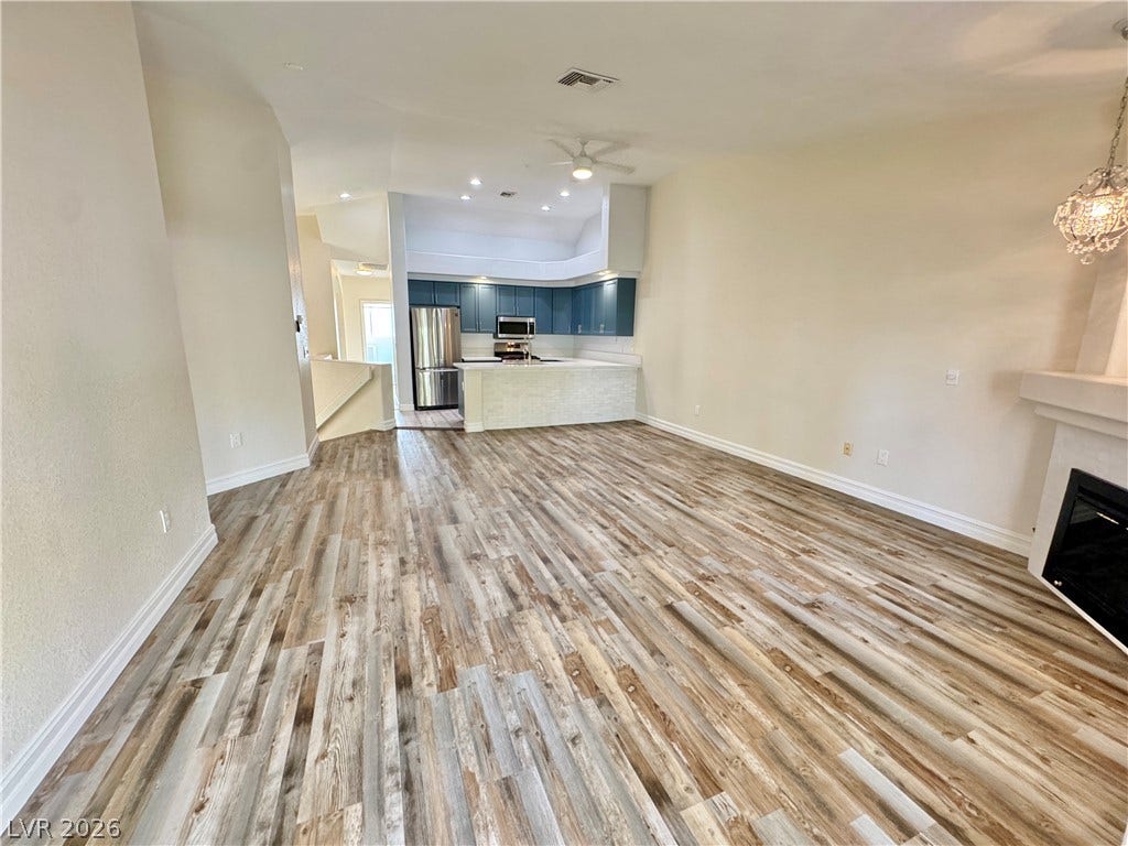 Polished wood floors stretch across this open living space anchored by a modern fireplace.