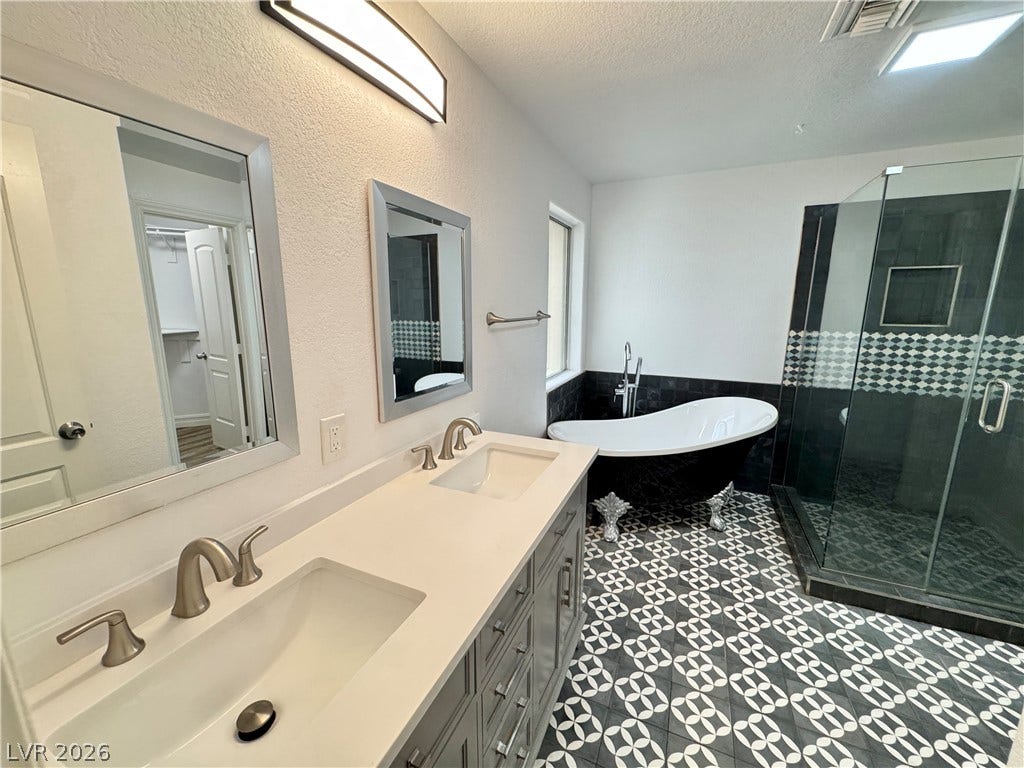 Striking patterned tile floors ground a bathroom equipped with a double vanity and soaking tub.