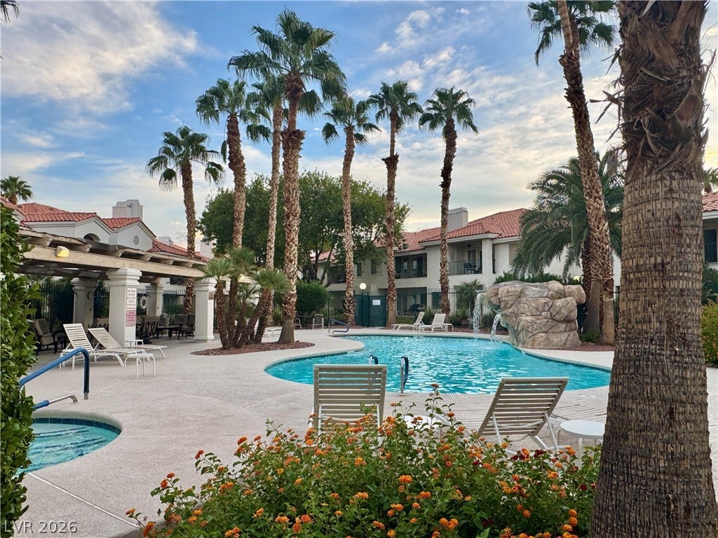 Lush palm trees and rock waterfall details create a relaxing resort-style swimming pool oasis.