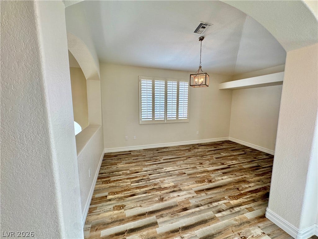 Rich wood-inspired flooring and architectural arched entries define this versatile interior space.