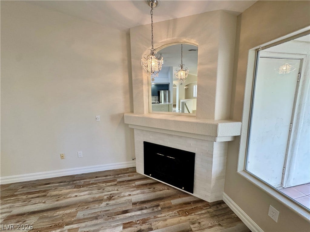 Rich wood-look flooring and a tiled fireplace under an arched cutout create architectural charm.