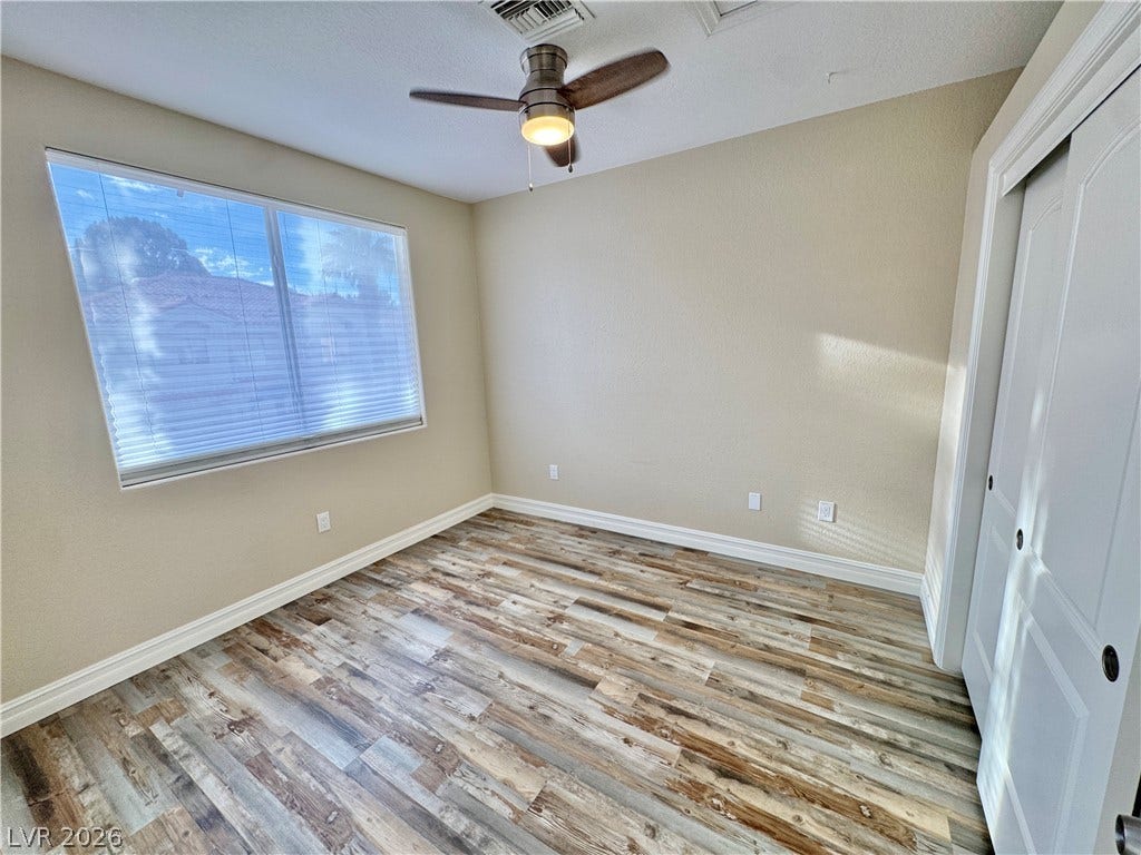 Gleaming wood-look floors and a wide window define this comfortable secondary bedroom.