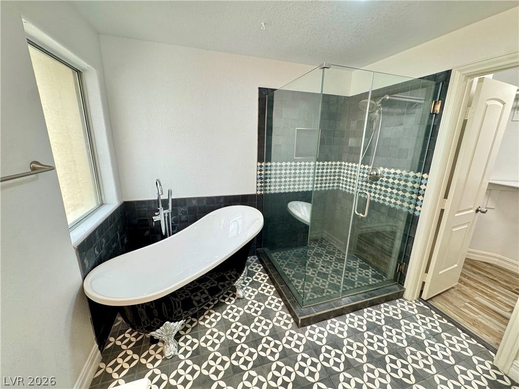 Ornate pattern tile floors highlight this bathroom with a clawfoot tub and glass shower.
