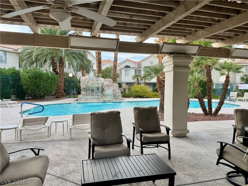 A shaded patio overlooks the sparkling community pool with its cascading rock waterfall feature.