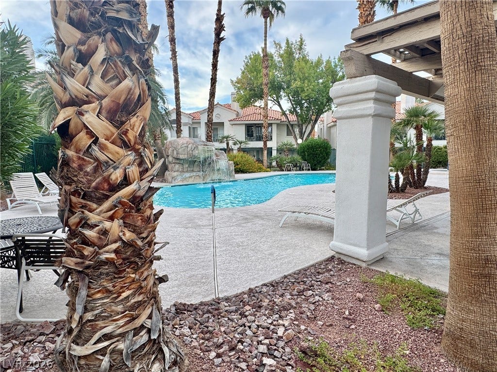 Mature palms and a stone waterfall frame the inviting swimming pool.