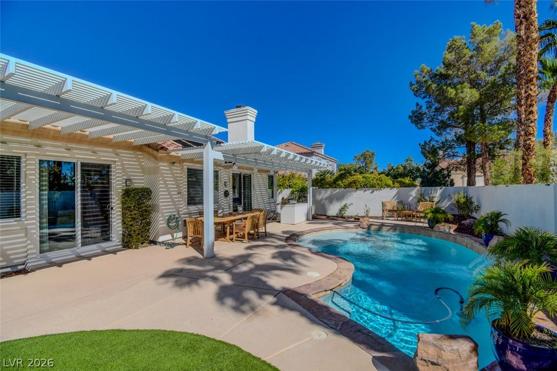 An inviting backyard oasis features a sparkling swimming pool alongside a spacious covered patio.