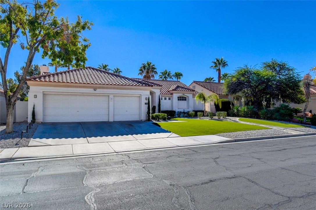 Spanish tile roofing and a wide concrete driveway define this classic suburban exterior.