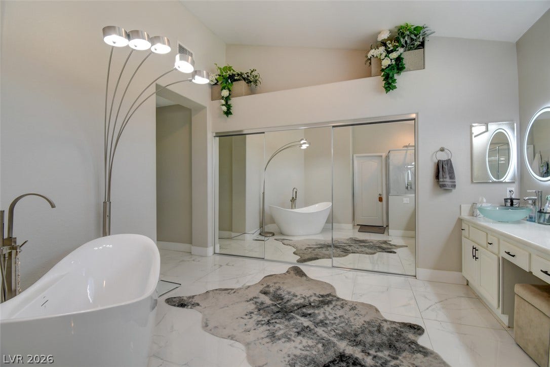 Polished tile flooring and a sleek soaking tub define this elegant primary bathroom.