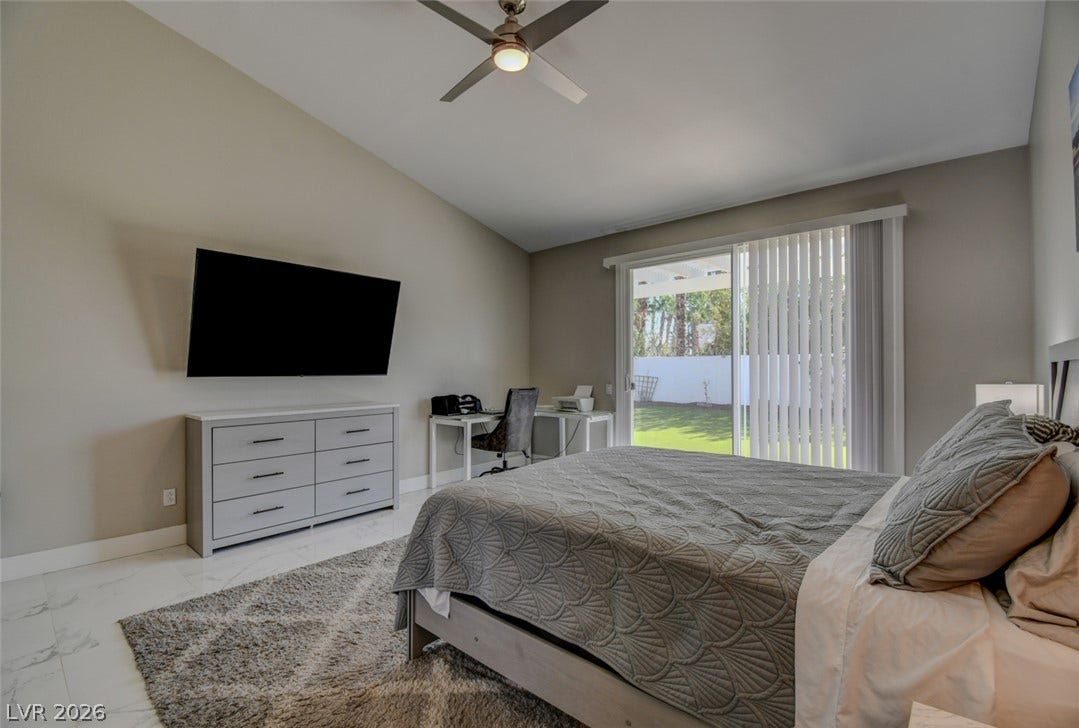 Sliding glass doors open directly to the green backyard from this vaulted bedroom.