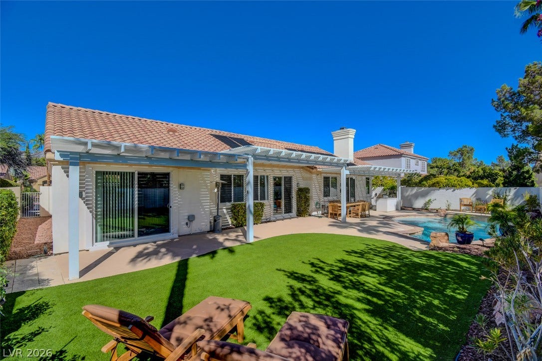 An inviting backyard oasis features a classic tile roof, manicured lawn, and sparkling swimming pool.