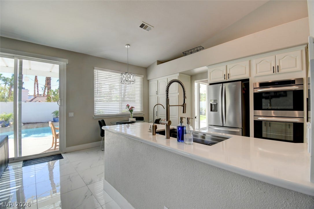 Gleaming tile floors and stone countertops anchor this modern kitchen with pool views.