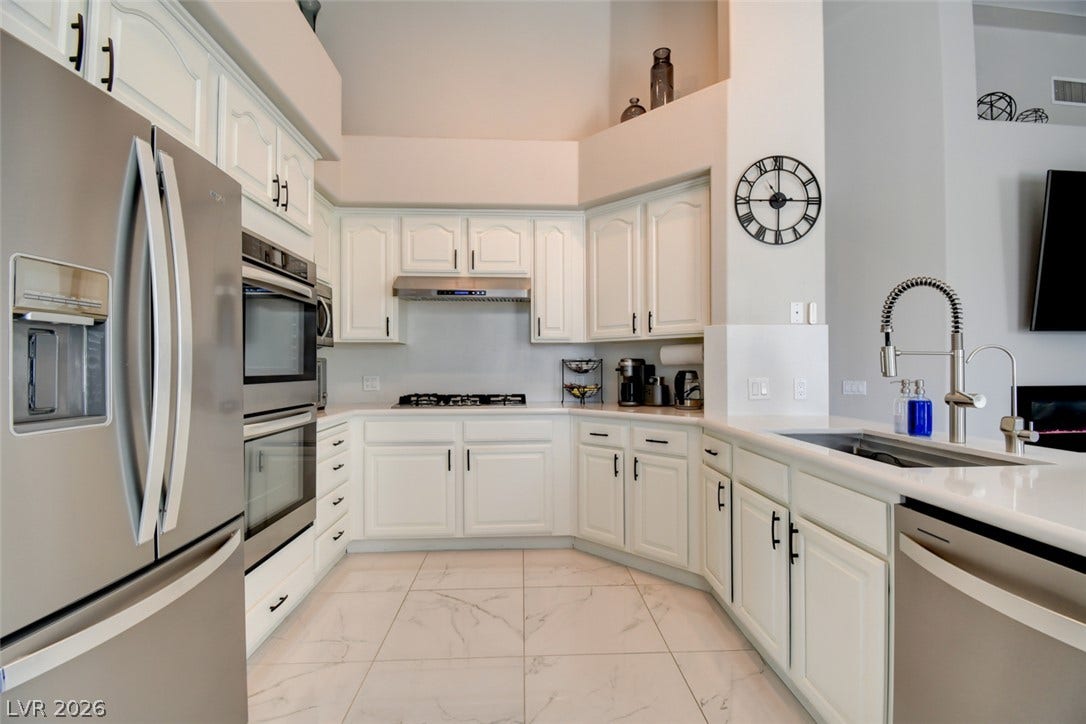 High vaulted ceilings and sleek stone countertops define this modern, light-filled kitchen space.