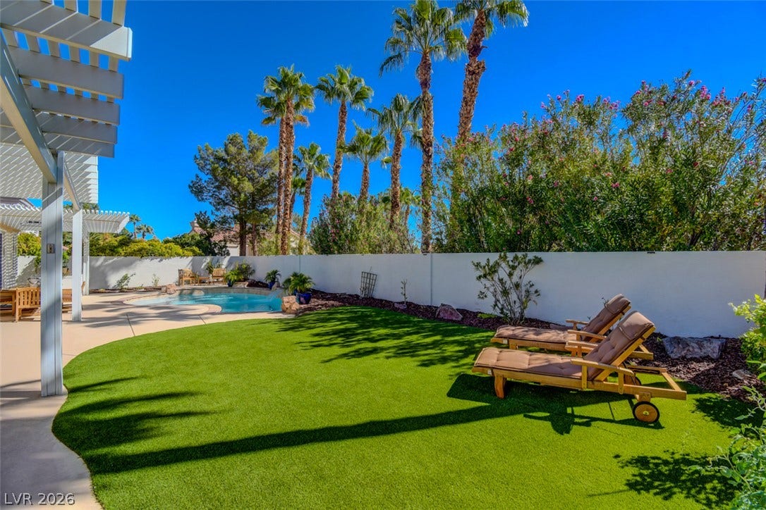 Lush artificial turf and towering palm trees frame this private backyard oasis with a sparkling pool.