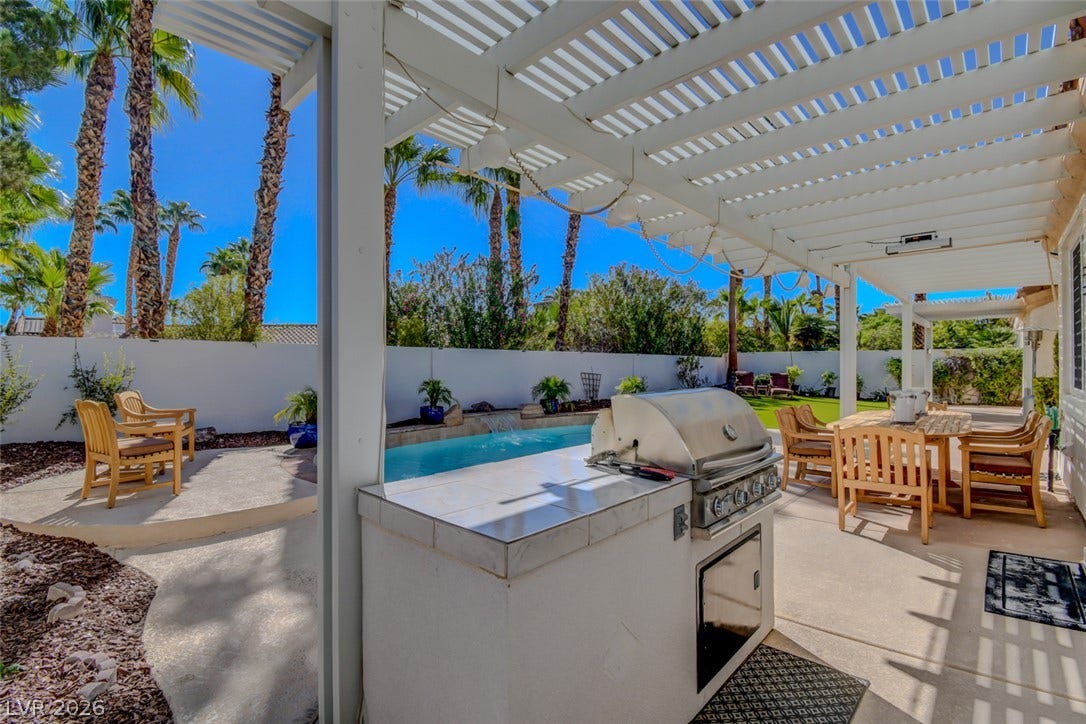 A spacious covered patio area features a built-in barbecue station overlooking a private swimming pool.