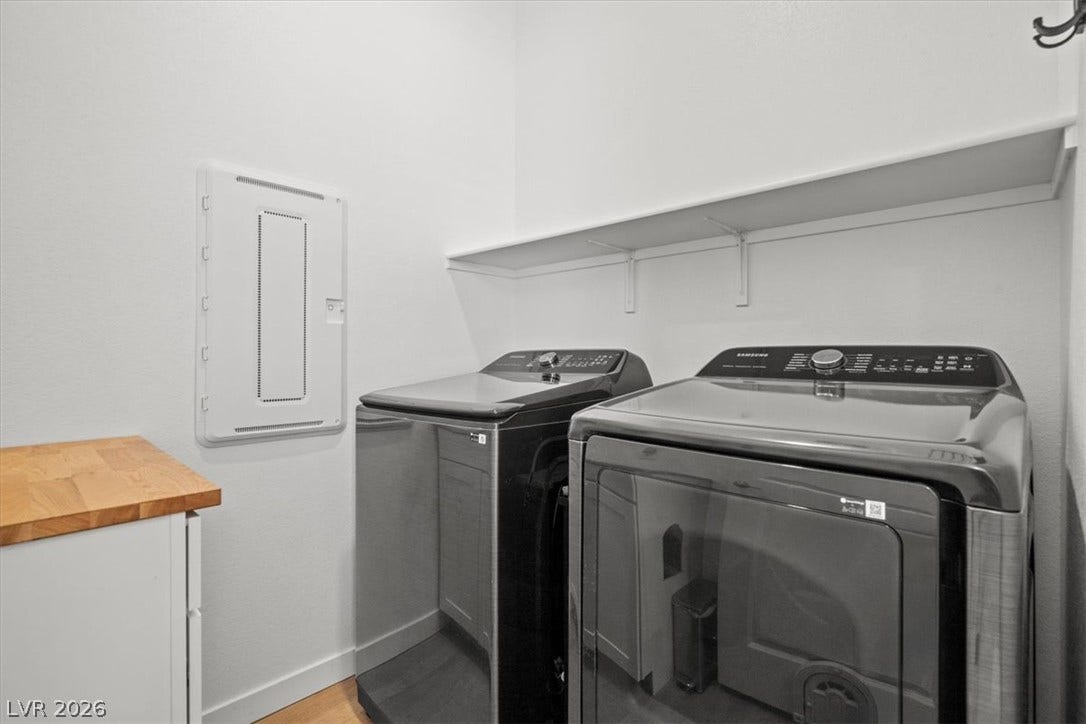 An organized laundry room features modern appliances and functional overhead shelving.