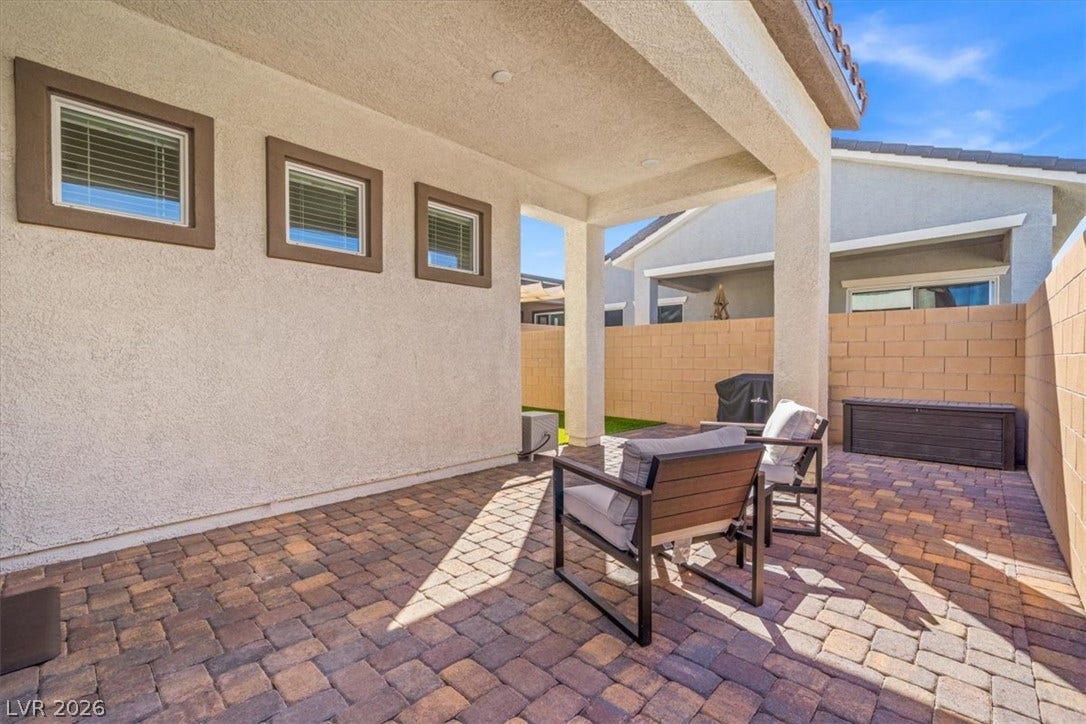 A covered patio lined with textured pavers provides a private outdoor retreat.