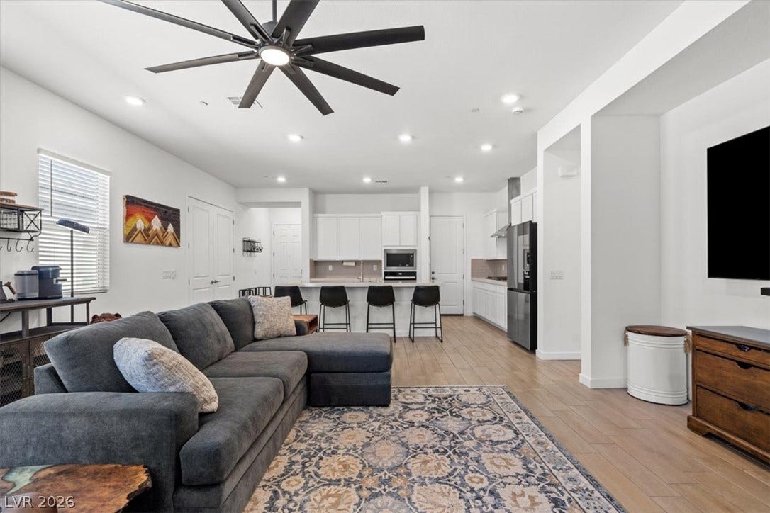 Recessed lighting and warm wood-style flooring enhance this open-concept layout.