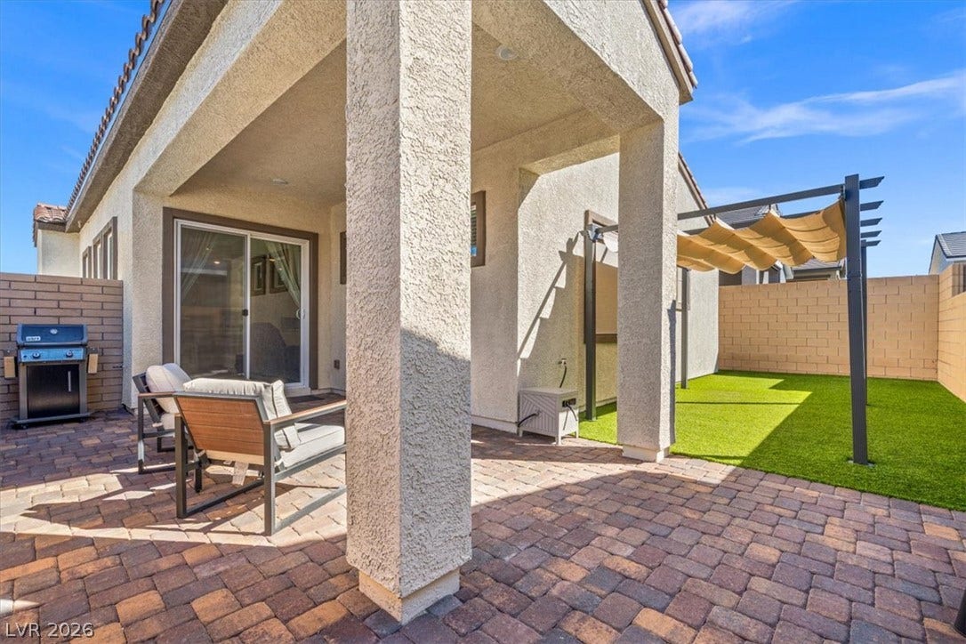 A spacious brick paver patio transitions smoothly into a low-maintenance artificial turf yard.