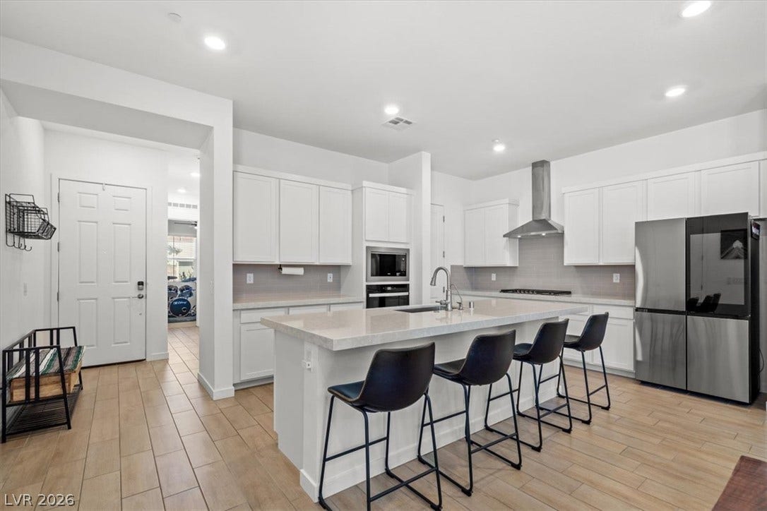 An expansive central island highlights this contemporary kitchen featuring light-toned flooring and built-in appliances.