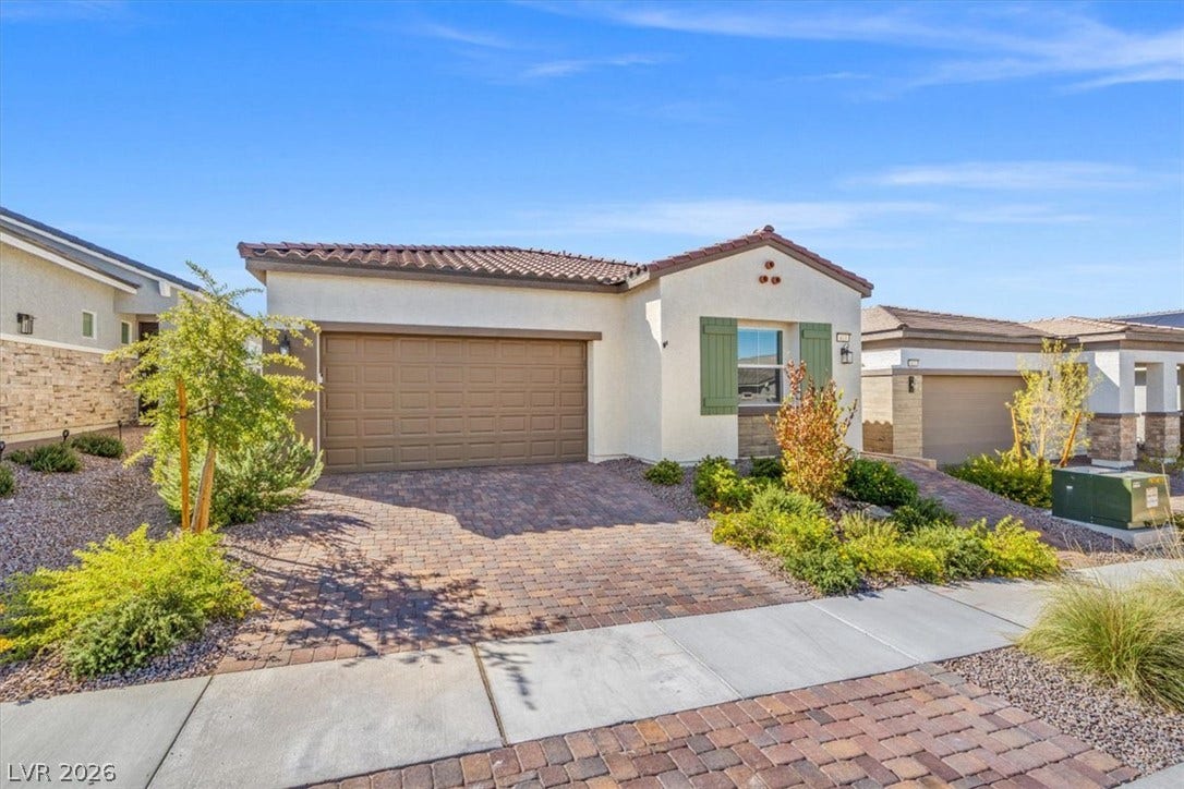 Desert landscaping and a paved driveway complement this modern single-story residence under clear blue skies.