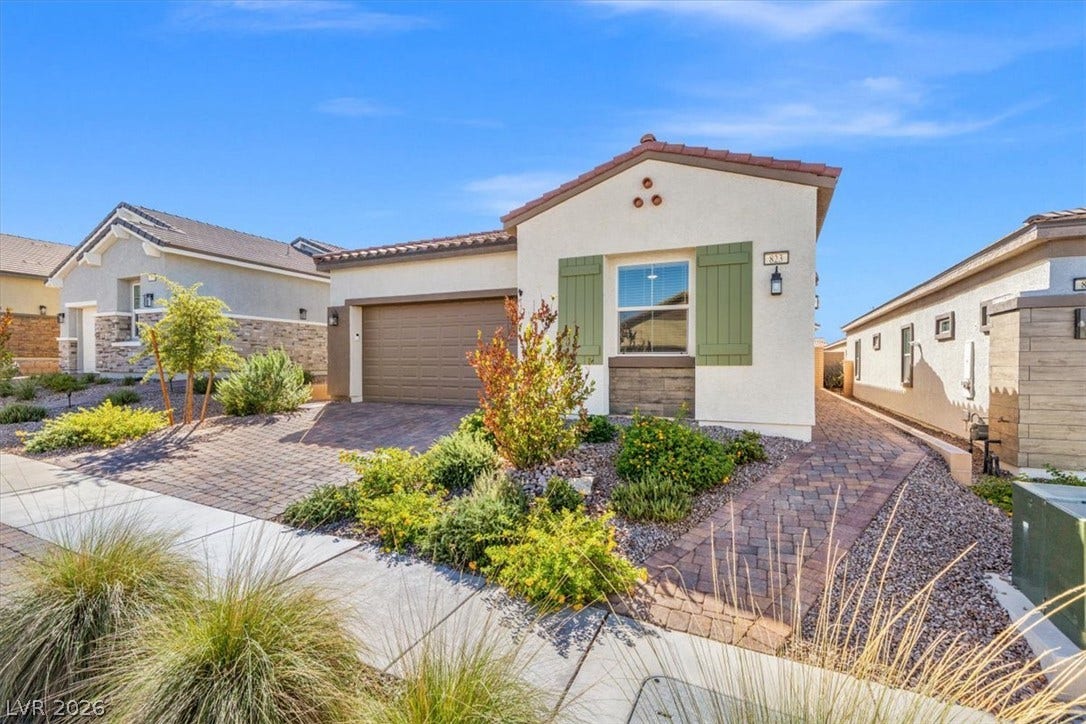 Inviting exterior features a paved driveway and desert landscaping under clear blue skies.