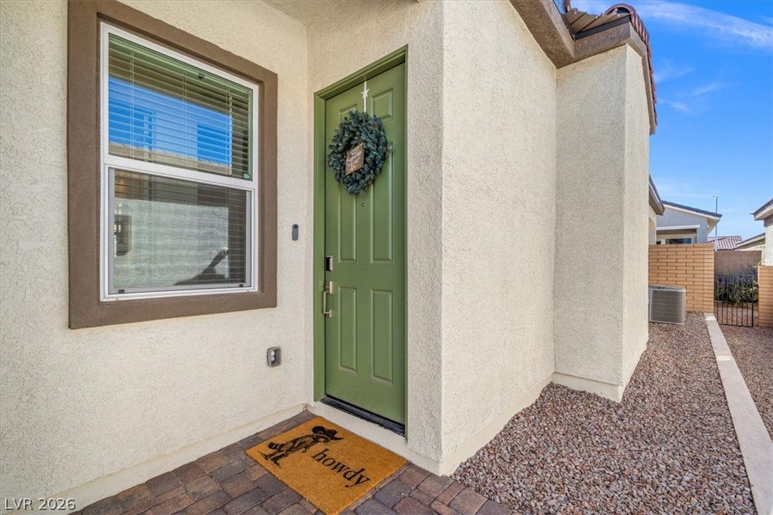 Welcoming entryway showcases textured stucco walls and classic stone paver detailing.