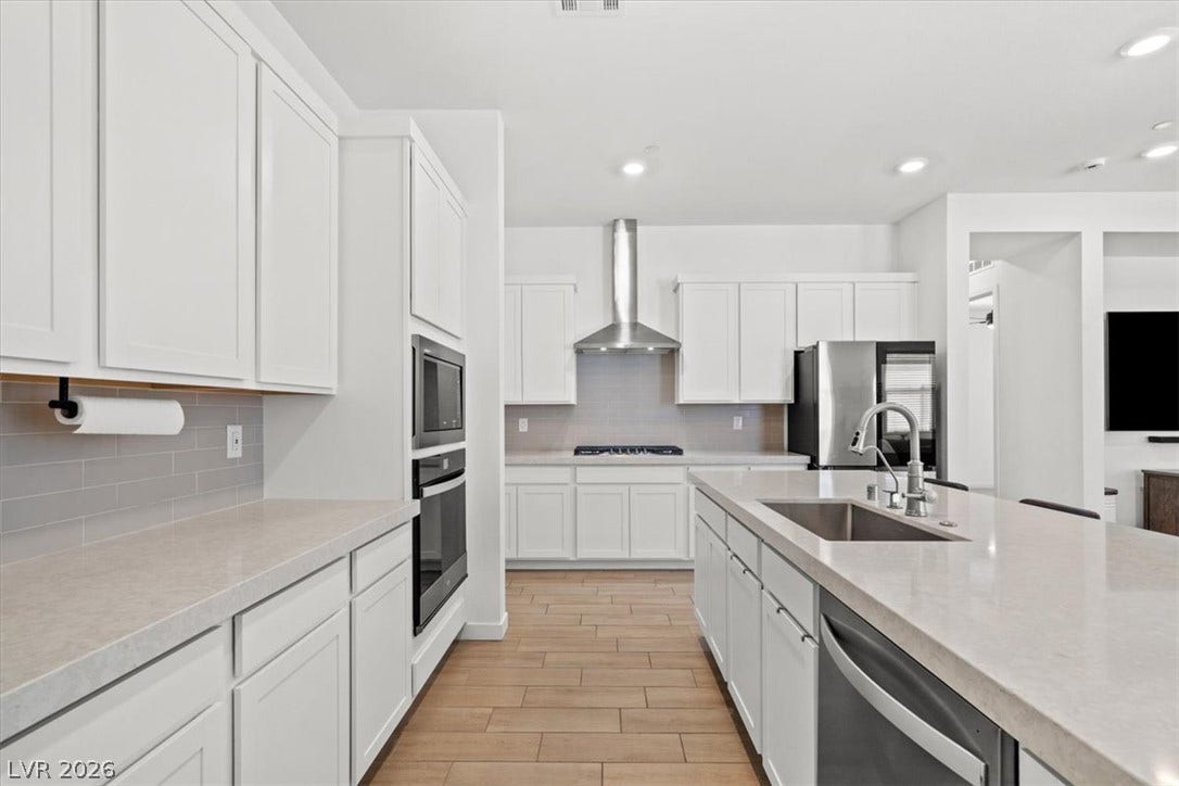 Smooth stone countertops pair with clean cabinetry and warm wood-look tile flooring in this kitchen.