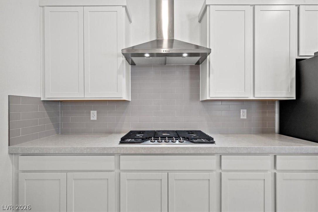Sleek stone countertops and classic shaker cabinetry surround a modern built-in gas cooktop.