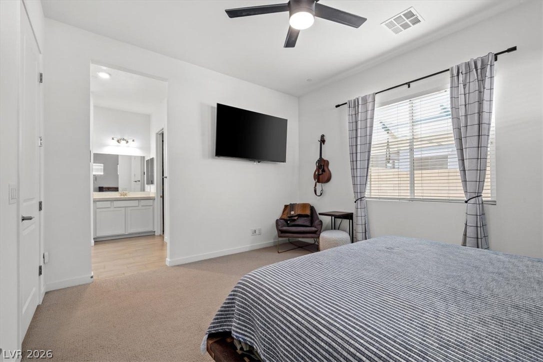 An inviting bedroom features plush carpeting and a large window looking out toward the neighborhood.