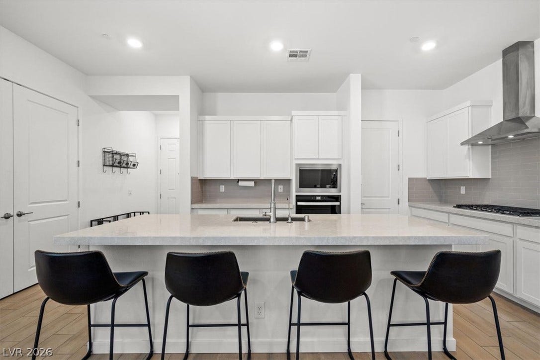 An expansive central island anchors this contemporary culinary space with clean stone surfaces.