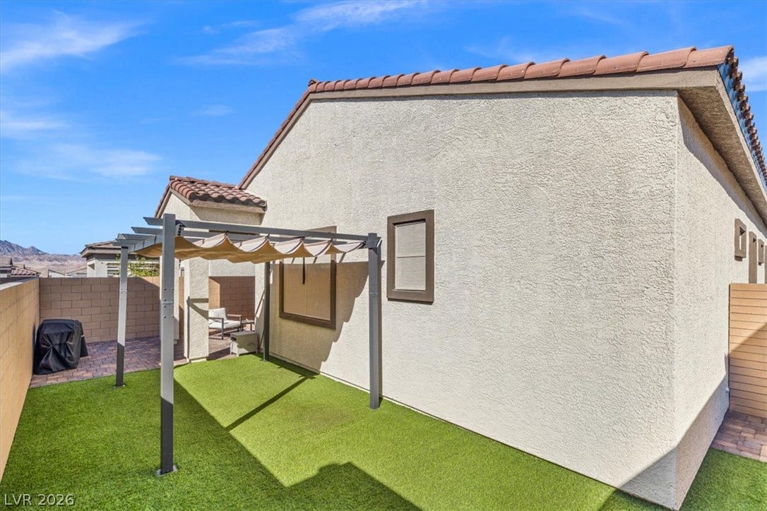 Low-maintenance turf and a shaded pergola define this tidy backyard retreat.