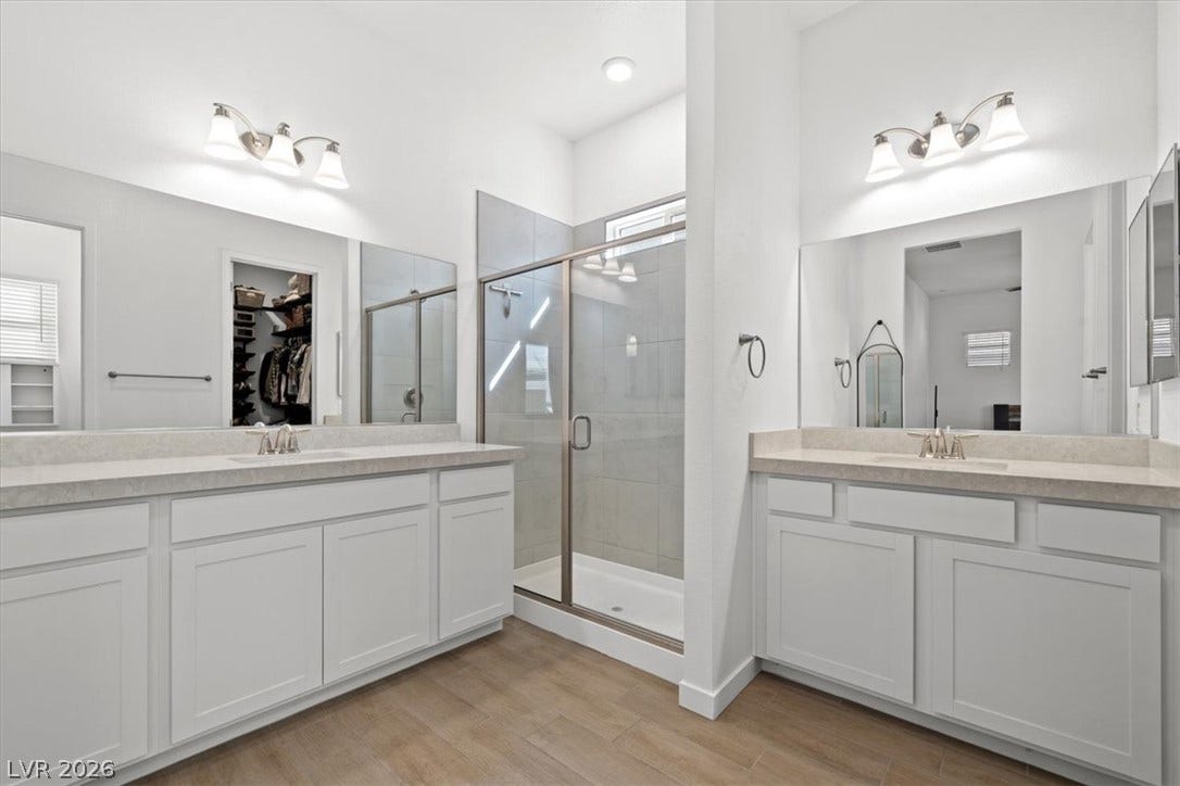 Dual vanities and a glass-enclosed walk-in shower highlight this modern primary bathroom.