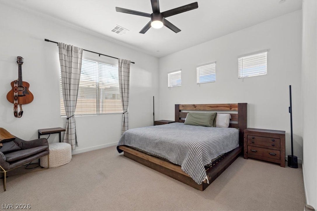 A spacious secondary bedroom features clean lines and plush carpeting.